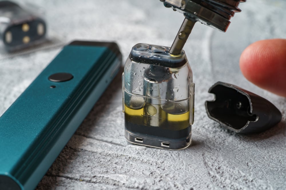cum umpli corect un pod - alimentarea unui cartus transparent cu lichid langa un dispozitiv vape turcoaz
